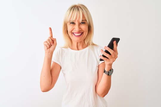 Middle age woman using smartphone standing over isolated white background surprised with an idea or question pointing finger with happy face, number one