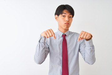 Chinese businessman wearing elegant tie standing over isolated white background Pointing down looking sad and upset, indicating direction with fingers, unhappy and depressed.