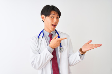 Chinese doctor man wearing coat tie and stethoscope over isolated white background amazed and smiling to the camera while presenting with hand and pointing with finger.