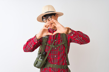 Chinese hiker man wearing backpack canteen glasses hat over isolated white background smiling in love showing heart symbol and shape with hands. Romantic concept.