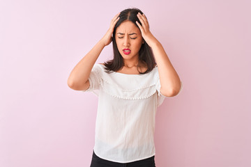 Obraz na płótnie Canvas Beautiful chinese woman wearing white t-shirt standing over isolated pink background suffering from headache desperate and stressed because pain and migraine. Hands on head.