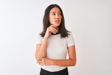 Obraz premium Young beautiful chinese woman wearing casual t-shirt standing over isolated white background with hand on chin thinking about question, pensive expression. Smiling with thoughtful face. Doubt concept.
