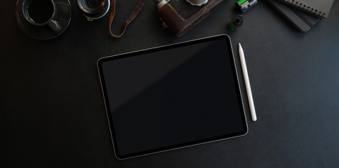 Dark trendy workspace with tablet and office supplies on black leather background