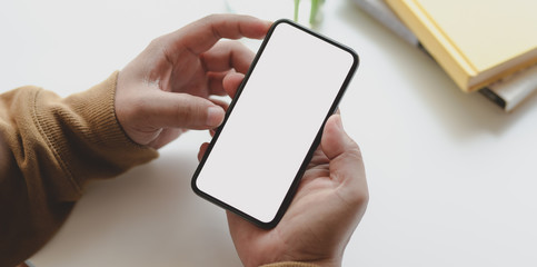 Close-up view of man holding blank screen smartphone while working on his project