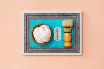 Shaving brush shaving with lather and a blade in the frame against the wall. The concept of body care. Hygiene.