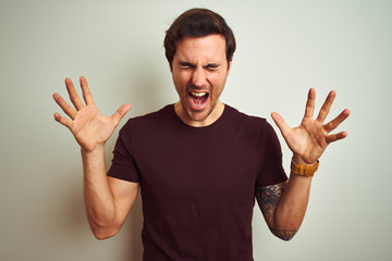 Young handsome man with tattoo wearing purple casual t-shirt over isolated white background...
