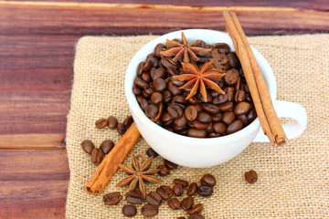 aroma roasted coffee beans in white cup with cinnamon,anise on retro wood floor