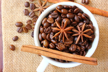 aroma roasted coffee beans in white cup with cinnamon,anise on retro wood floor