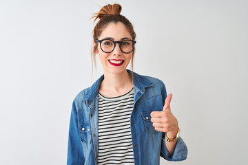Redhead woman wearing striped t-shirt denim shirt and glasses over isolated white background doing...