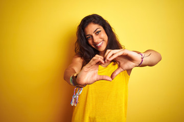 Young beautiful woman wearing t-shirt standing over isolated yellow background smiling in love...