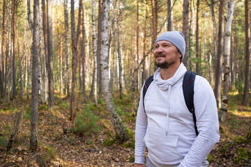 Naklejka na ściany i meble Tourist or traveler with a backpack in the autumn forest. Hiking. 