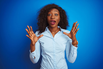 African american businesswoman wearing shirt standing over isolated blue background celebrating crazy and amazed for success with arms raised and open eyes screaming excited. Winner concept