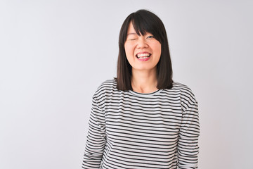 Young beautiful chinese woman wearing black striped t-shirt over isolated white background winking...