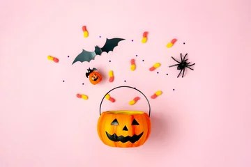 Foto op Canvas Table top view aerial image of decorations Happy Halloween day background holiday concept.Flat lay objects to party Jack O lantern pumpkins bucket and spider with candy sweet on pink  paper. © osabee