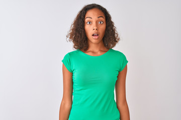 Young brazilian woman wearing green t-shirt standing over isolated white background afraid and shocked with surprise expression, fear and excited face.