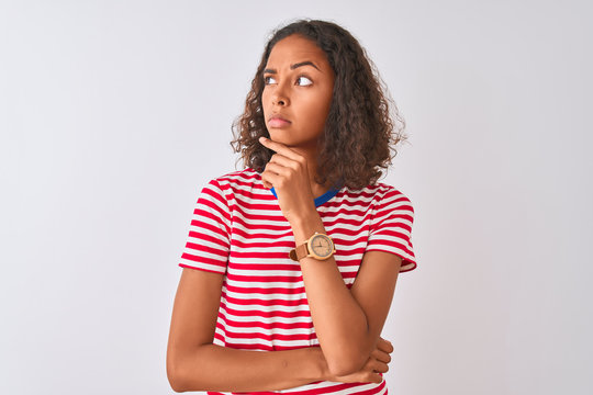 Young brazilian woman wearing red striped t-shirt standing over isolated white background Thinking worried about a question, concerned and nervous with hand on chin
