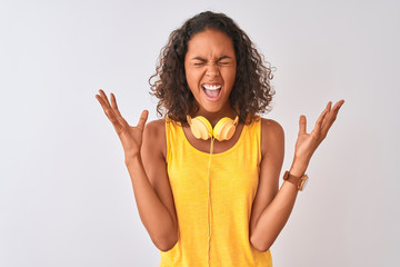 Young brazilian woman wearing yellow headphones over isolated white background celebrating mad and...