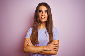Young beautiful woman wearing casual t-shirt standing over isolated pink background skeptic and...