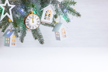 new year ornaments with christmas tree branch, decorative toy stars, houses, watches and glowing color garland lights
