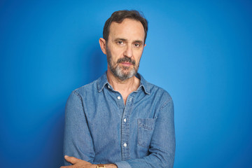 Handsome middle age senior man with grey hair over isolated blue background Relaxed with serious expression on face. Simple and natural looking at the camera.