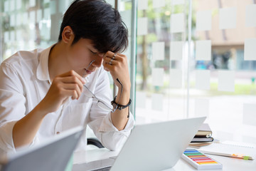 Young asian businessman feeling stressed and massaging his nose and keeping eyes closed. Tired...