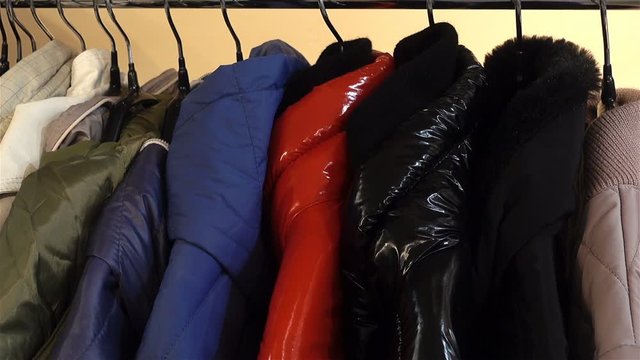 Women's jackets of various colors hanging on hangers in a row close-up.