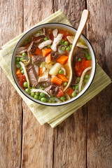 Booyah (booya, bouja, boulyaw, or bouyou) is a thick stew with vegetables and meat close-up in a bowl. Vertical top view