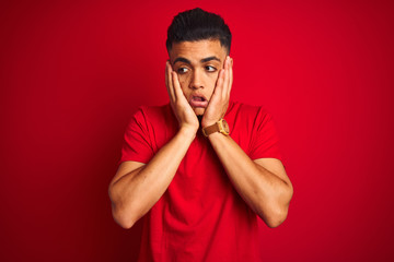 Young brazilian man wearing t-shirt standing over isolated red background Tired hands covering face, depression and sadness, upset and irritated for problem