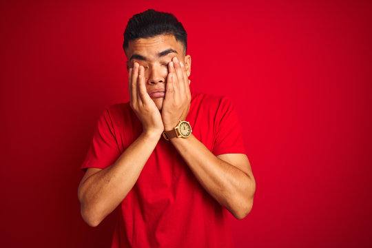 Young brazilian man wearing t-shirt standing over isolated red background rubbing eyes for fatigue and headache, sleepy and tired expression. Vision problem