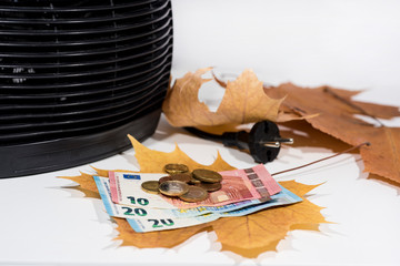 Money for heating bills with black heater on white background. Autumn season.