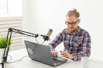 Radio, DJ, blogging and people concept - Smiling man sitting in front of microphone, host at radio