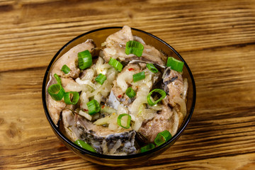 Marinated carp in glass bowl on wooden table