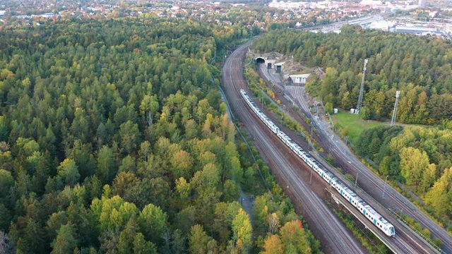 Aerial view of Stockholm forest and railroad. Drones flies over forest while train passes by, Sweden.
