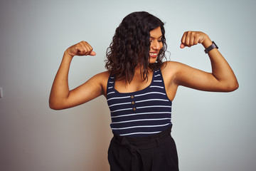 Transsexual transgender woman wearing striped t-shirt over isolated white background showing arms muscles smiling proud. Fitness concept.