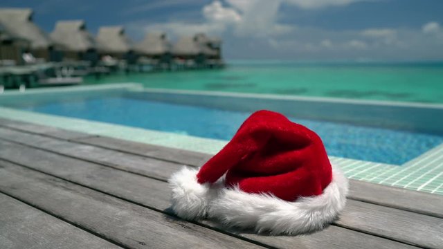 Christmas beach vacation with santa hat by swimming pool. Travel background for winter holidays luxury getaway holiday.
