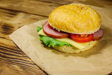 Fresh delicious homemade cheeseburger on brown paper on wooden table