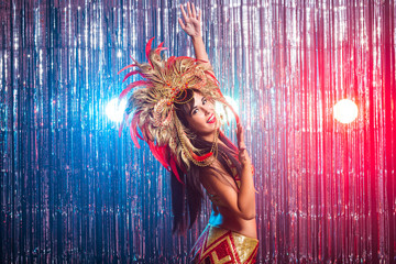 Carnival, dancer and holiday concept - Portrait of a sexy female in a colorful sumptuous carnival feather suit. Nightlife of female dancer