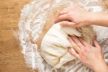 Woman's hands knead pizza dough