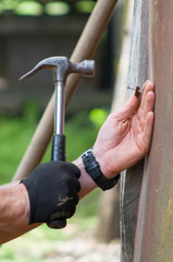 The carpenter is repairing the house. He makes nails using a hammer