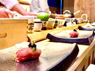 Closeup of chef hands preparing japanese food. Japanese Omakase Chef making sushi at restaurant. chef serving traditional japanese sushi with gold served on a stone plate.