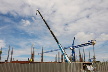 High rise building construction sites with cranes facilitating the transportation of materials and equipment On a bright sky background with white clouds