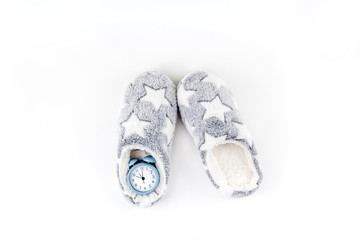 Soft fluffy slippers and blue alarm clock