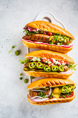 Hot dogs with different toppings on white background, top view. Fast food concept.