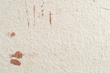 The textural surface of the wall of the house of fashionable color vanilla custard by the sun with a few red strokes of drops.