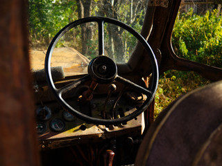 Controls the old tractor. Steering wheel and levers at the rusty tractor