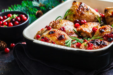 Christmas food. Baked Chicken meat with cranberries and rosemary in the oven dish, dark background.