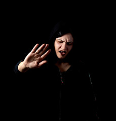 The woman in the hood cries, and shows a hand stop, not on a dark background.