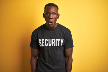 African american safeguard man wearing security uniform over isolated yellow background afraid and shocked with surprise expression, fear and excited face.