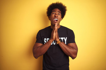 American safeguard man with afro hair wearing security uniform over isolated yellow background...