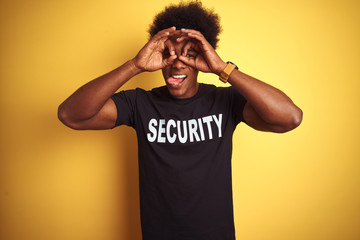 American safeguard man with afro hair wearing security uniform over isolated yellow background...